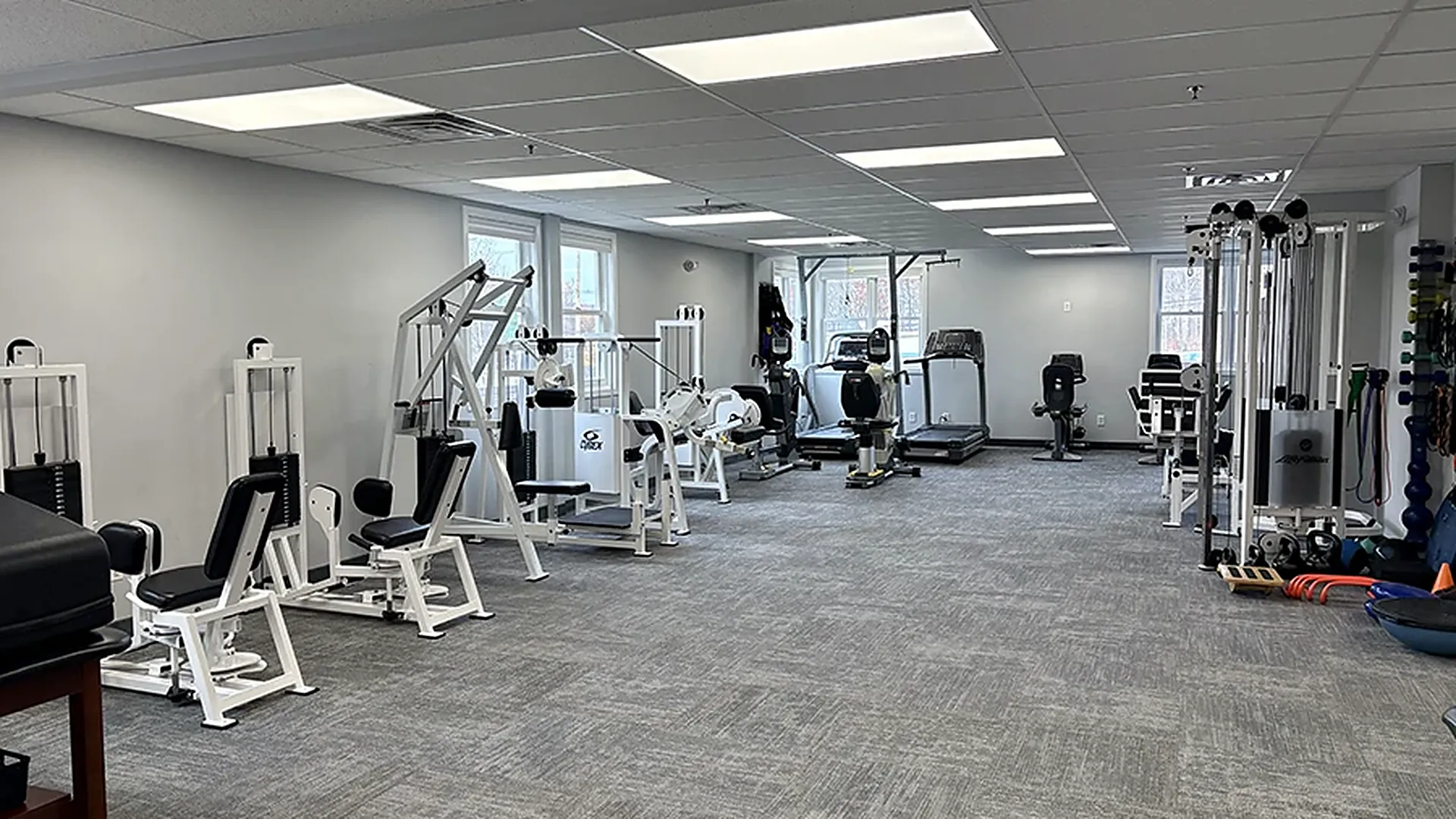 The exercise floor at Carroll Physical Therapy in Denville, NJ, with strength machines, a treadmill, a recumbent bike, and a cable column