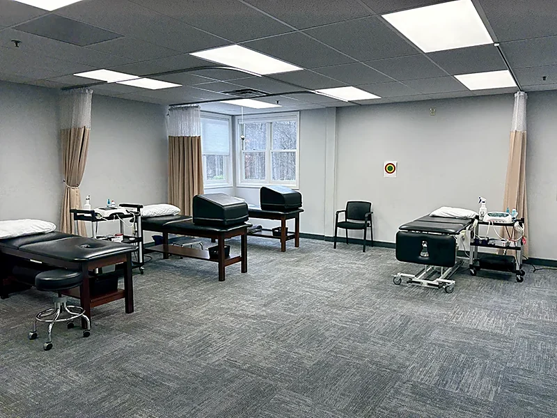 Treatment tables, curtained privacy bays, and a rolling stool in the Denville, NJ clinic at Carroll Physical Therapy
