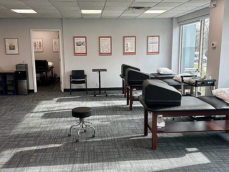 A treatment room at the Mountain Lakes, NJ clinic at Carroll Physical Therapy, with treatment tables along a window wall and framed anatomy charts