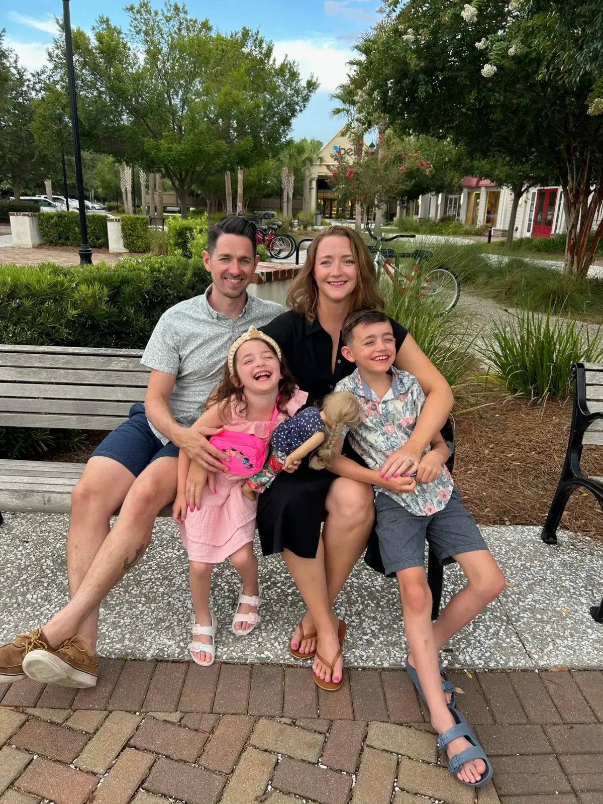 Physical therapist Dan Streeter of Carroll Physical Therapy sitting on an outdoor bench with his wife, their young daughter and their son, all smiling on a summer day