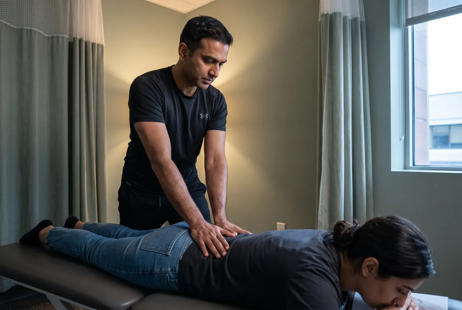 A physical therapist performing hands-on manual therapy on a patient's back