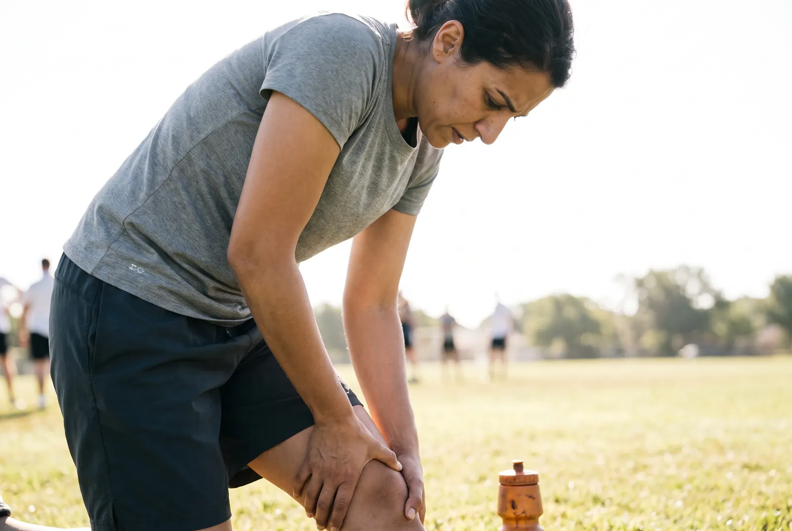 A physical therapist attending to an athlete's injury outdoors on the field